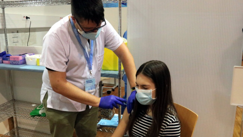 Pla mitjà d'un infermer administrant la vacuna contra la covid-19 a una jove al pavelló Onze de Setembre de Lleida, l'11 d'agost del 2021.