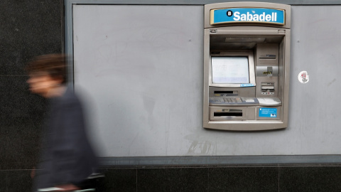 Una mujer pasa por delante de un cajero automático de una oficina del Banco Sabadell en Barcelona. REUTERS/Yves Herman