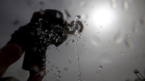 Un hombre se refresca en una de las fuentes de la ciudad para aliviar las altas temperaturas.