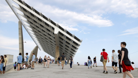 Assistents al festival Primavera Sound passen per sota la gegantina placa fotovoltaica del Fòrum, a Barcelona.