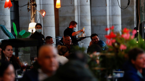 Un camarero atiende una mesa en una de las terrazas de la madrileña Plaza Mayor. REUTERS/Susana Vera