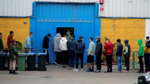 17/11/2021 Varios migrantes hacen cola ante una nave de Cruz Roja este miércoles en Ceuta.