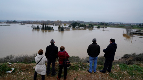 Varias personas observan los edificios de una granja sumergidos después de fuertes lluvias e inundaciones en Zaragoza. REUTERS / Vincent West