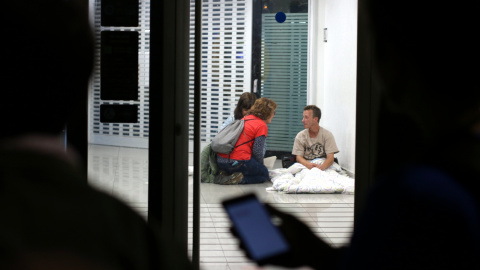 Dins un caixer la Berta i la Clara conversen amb un home mentre la resta de voluntaris del grup els espera a fora durant el cens de persones sense llar de Barcelona.