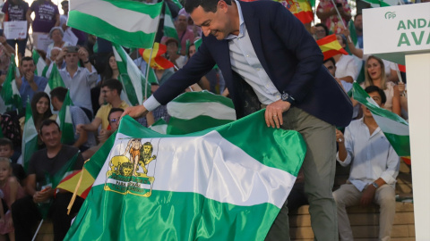 Juanma Moreno torea con una bandera de Andalucía en el inicio de la campaña a los comicios al Parlamento.