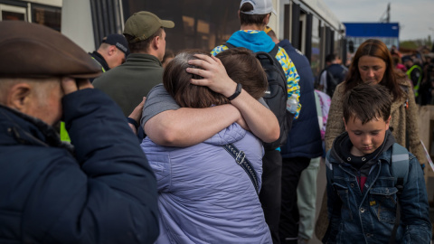 Refugiados ucranianos se abrazan este martes 3 de mayo de 2022 tras llegar al estacionamiento de un centro comercial en Zaporiyia (Ucrania).
