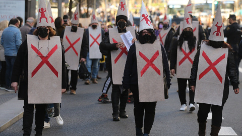 Varios manifestantes vestidos con petos tachados con cruces y capirotes blancos con niños dibujados, durante la manifestación en defensa de los menores tutelados, en el centro de Madrid el 29 de enero de 2022.