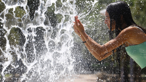 10/07/2022 Una mujer se refresca en una de las fuentes del centro de Córdoba este domingo