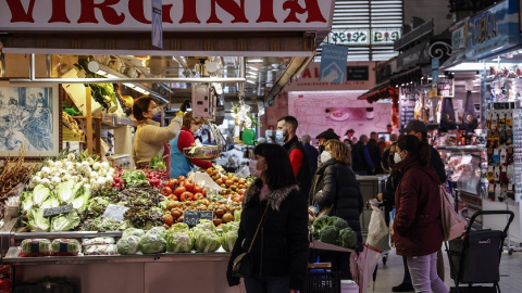 Varias personas compran en un puesto de fruta y verdura en el Mercado Central de Valencia, a 24 de marzo de 2022, en Valencia, Comunidad Valenciana, (España).