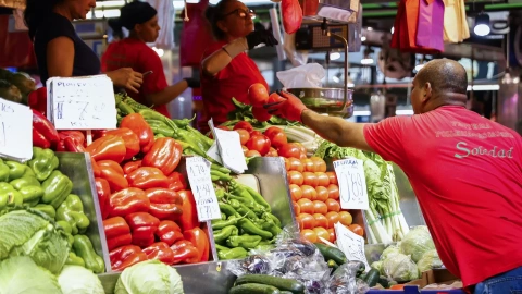 Un hombre compra en un puesto de fruta y verduras de un mercado de Madrid.