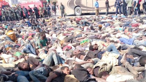 Decenas de migrantes se desparraman por el suelo, custodiados por la policía marroquí, tras el intento de salto a la valla de Melilla en el que han muerto al menso 27 personas.