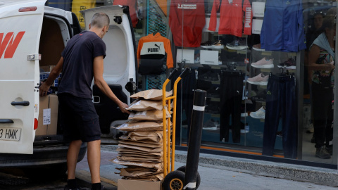 Un repartidor prepara paquetes de ropa en un carrito, en frente de un comercio en la localidad malagueña de Ronda. REUTERS/Jon Nazca