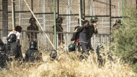 Un miembro de las fuerzas de seguridad marroquíes conduce desde suelo español a uno de los migrantes que logró saltar la valla de Melilla el pasado viernes.