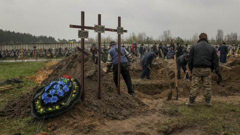 Varias personas entierran un cuerpo en el cementerio de Bucha (Ucrania) el 22 de abril de 2022.