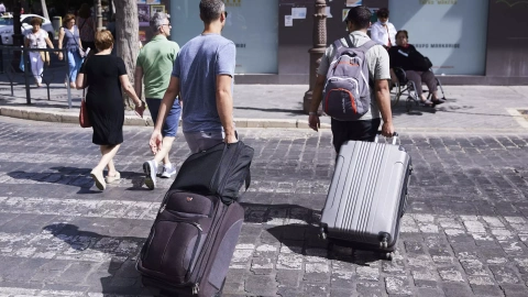 Dos turistas con maletas cruzan un paso de peatones en Sevilla.