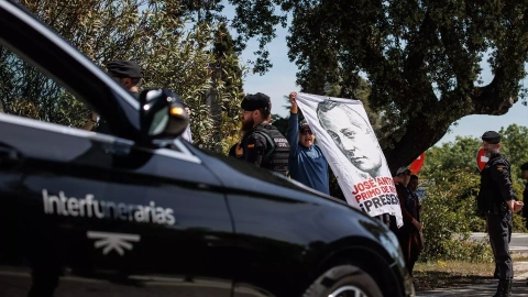 El coche fúnebre con los restos de José Antonio Primo de Rivera, salen de la basílica del Valle de Cuelgamuros, mientras simpatizantes de la falange sujetan una tela con su rostro, a 24 de abril de 2023, en San Lorenzo de El Escorial, Madri