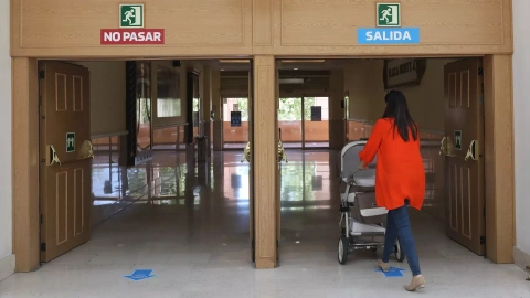 29/03/2023 Una mujer con un carrito de bebé sale de un edificio.