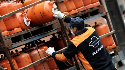 Un butanero coge una bombona de butano del camión.