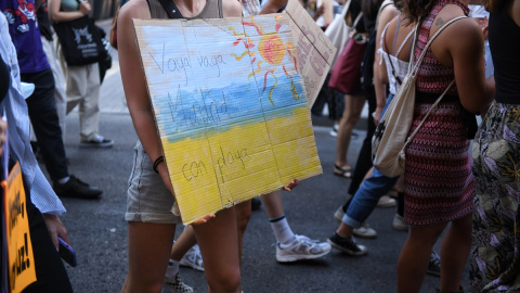 Una joven sostiene una pancarta en una manifestación por el clima para exigir un cambio en el sistema energético, en la Plaza Mayor, en Madrid (España).