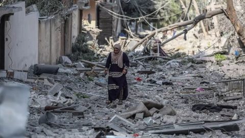 Una mujer palestina recorre una calle de la ciudad de Gaza cubierta de escombros por los bombardeos de la aviación israelí, que se mantienen por quinto día consecutivo.