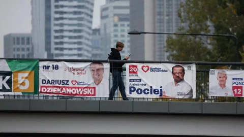 Un hombre camina cerca de carteles electorales exhibidos en el centro de la ciudad de Varsovia, antes de las elecciones parlamentarias del domingo.