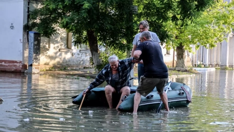 06/06/2023 - Dos personas ayudan a un anciano a subirse a un bote inflable mientras evacua de su casa en una calle inundada de Kherson, Ucrania, a 6 de junio de 2023.