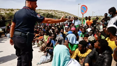 Un policía italiano habla a los migrantes que han llegado a la isla siciliana de Lampedusa, a 18 de septiembre de 2023