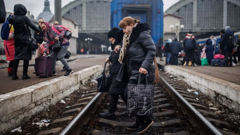 Dos mujeres cruzan las vías de la estación de tren de Leópolis para huir a la vecina Polonia tras la invasión rusa de Ucrania, a 4 de marzo de 2022.
