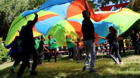 Un grup de nens jugant sota un llençol de colors en una Festa Esplai, en ua imatge d'arxiu