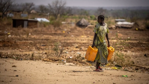 Una mujer camina por la carretera con bidones de agua, a 26 de enero de 2024 en Sudán del Sur, Juba.