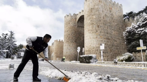 Un hombre limpia la calle de nieve frente a las murallas de Ávila (España) el 3 de marzo de 2024.