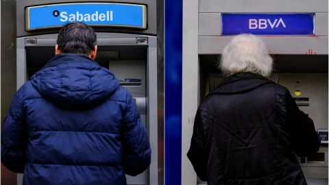 Dos personas usan los cajeros del BBVA y del Banco Sabadell en imágenes de archivo.