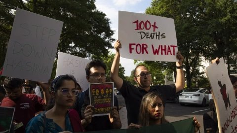 Manifestantes de la comunidad bangladesí muestran carteles con los mensajes ''100+ Muertes ¿Para Qué?'' y otros textos informativos durante una protesta frente a la Embajada de Bangladesh en Washington DC, Estados Unidos