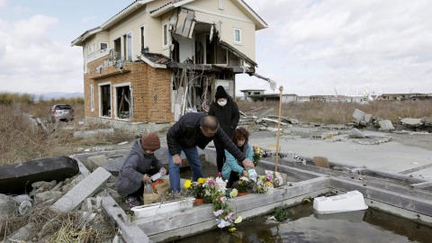 Una familia coloca flores y ora por sus parientes víctimas del terremoto y el tsunami del 11 de marzo de 2011 en el país. EFE/KIMIMASA MAYAMA