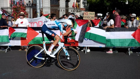 Un ciclista pasa por delante de banderas y pancartas en apoyo a Palestina durante la etapa final de la Vuelta en Madrid, a 8 de septiembre de 2024.