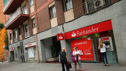 Una mujer utiliza el cajero automático de una oficina del Banco Santander, ubicado junto a un sucursal del Banco Popular, en Barcelona. REUTERS/Albert Gea