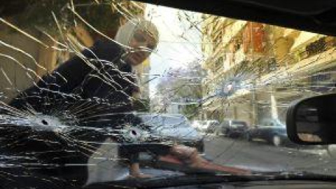 La vida no se para con la guerra. Una mujer limpia en Beirut el parabrisas de su coche que presenta varios impactos de bala. bela szandelsky / ap