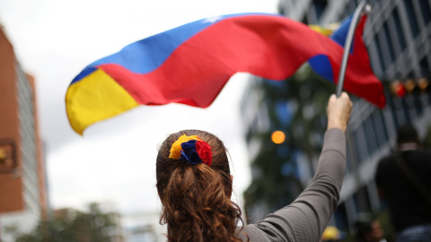 Una mujer ondea una bandera de Venezuela durante una manifestación en contra de Nicolás Maduro. / REUTERS - ANDRES MARTINEZ CASARES