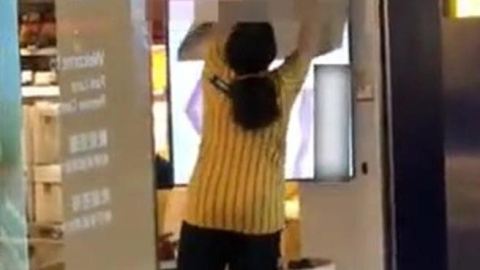 Una trabajadora de Ikea intenta tapar la pantalla del escaparate de una de las tiendas del gigante sueco en Hong Kong.