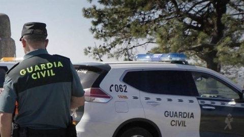 Agente de la Guardia Civil junto a un coche patrulla. GUARDIA CIVIL
