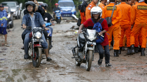 Residentes locales con sus scooters en una carretera embarrada después de un tsunami en el Estrecho de Sunda en Pandeglang, Banten, Indonesia.- EFE/EPA/ADI WEDA