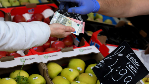 Un cliente paga su compra en un puesto de frutas y verduras de un mercado de Madrid. REUTERS/Sergio Perez