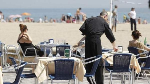 Un camarero atiende las mesas de un restaurante junto a la playa. EFE