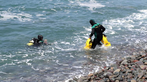 Dos submarinistas de la Guardia Civil se preparan para sumergirse y continuar con la búsqueda de los inmigrantes desaparecidos en el mar tras desembarcar de una patera en el sur de Gran Canaria. /EFE