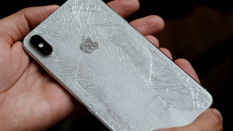 Un hombre sujeta un Smartphone de Apple, cuya carcasa posterior está agrietada./ REUTERS