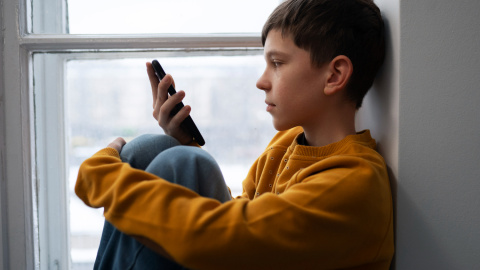 2150169533 Niño solo con teléfono móvil.