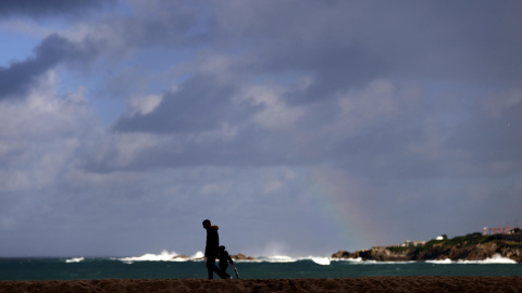 c940eb4057a798dd3ef116a5621a3375db70fcccw Un hombre camina con un niño este sábado por la playa de Riazor, en A Coruña, en una jornada en la que cuatro comunidades autónomas (Asturias, Cantabria, Galicia y el País Vasco) van a estar hoy en alerta amarilla (riesgo) por el fuerte oleaje que va a azotar al litoral, a la espera de la llegada mañana de la borrasca Herminia, un temporal con rachas de viento que podrían superar los 100 km/h en la cornisa cantábrica según la AEMET. EFE/Cabalar