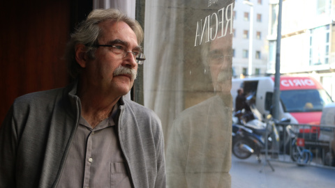 L'escriptor Jaume Cabré mirant a través d'un vidre el carrer, amb el seu reflex