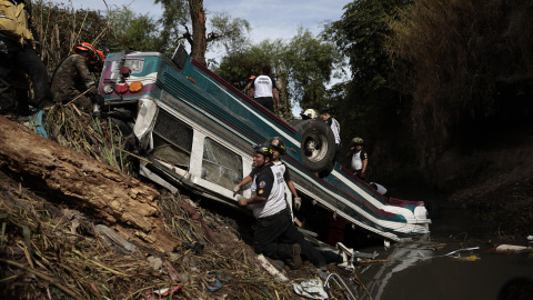 Bomberos voluntarios trabajan en la zona donde ha ocurrido el accidente de un autobús, que ha caído en un río de aguas residuales este lunes en el norte de la Ciudad de Guatemala (Guatemala).