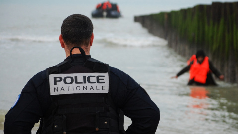 Un policía francés observa a un migrante que se acerca a la orilla después de intentar cruzar el Canal de la Mancha para llegar a Reino Unido.